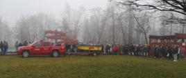 Zdjęcie przedstawia uczniów stojących wokół samochodu strażackiego z przyczepą, na której znajduje się łódka WOPR.