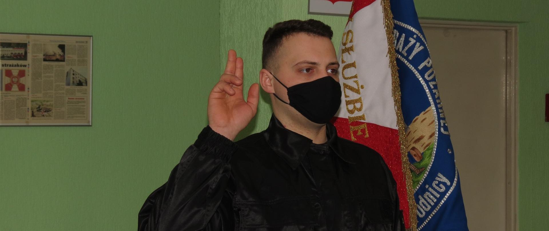 Zdjęcie przedstawia moment ślubowania strażaka Grzegorza Talkowskiego. Strażak Grzegorz Talkowski stoi obok sztandaru Komendy.