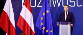 minister Przemysław Czarnek podczas konkresu 590. w tle hasło kongresu, po lewej stronie stoją flagi polski, Austrii i UE