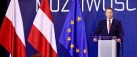 minister Przemysław Czarnek podczas konkresu 590. w tle hasło kongresu, po lewej stronie stoją flagi polski, Austrii i UE