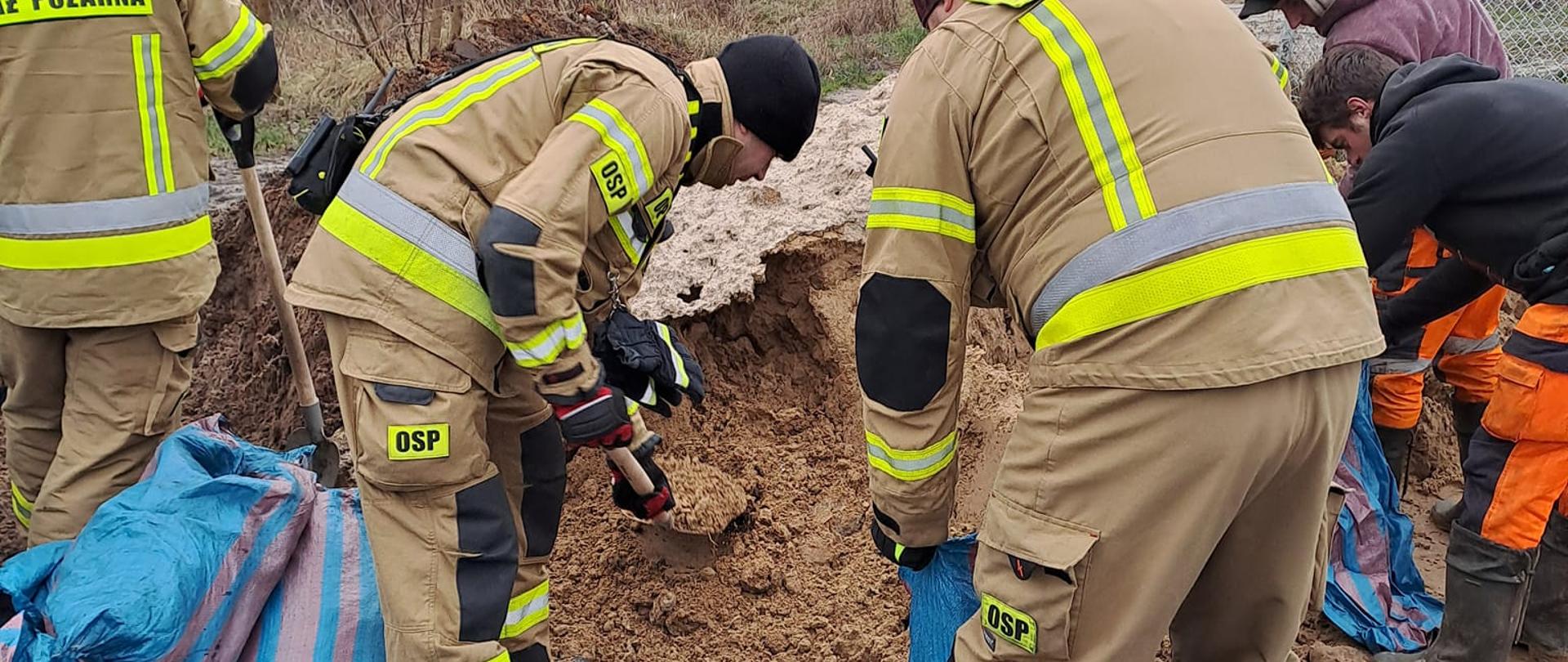 Strażacy wsypujący piasek do worków