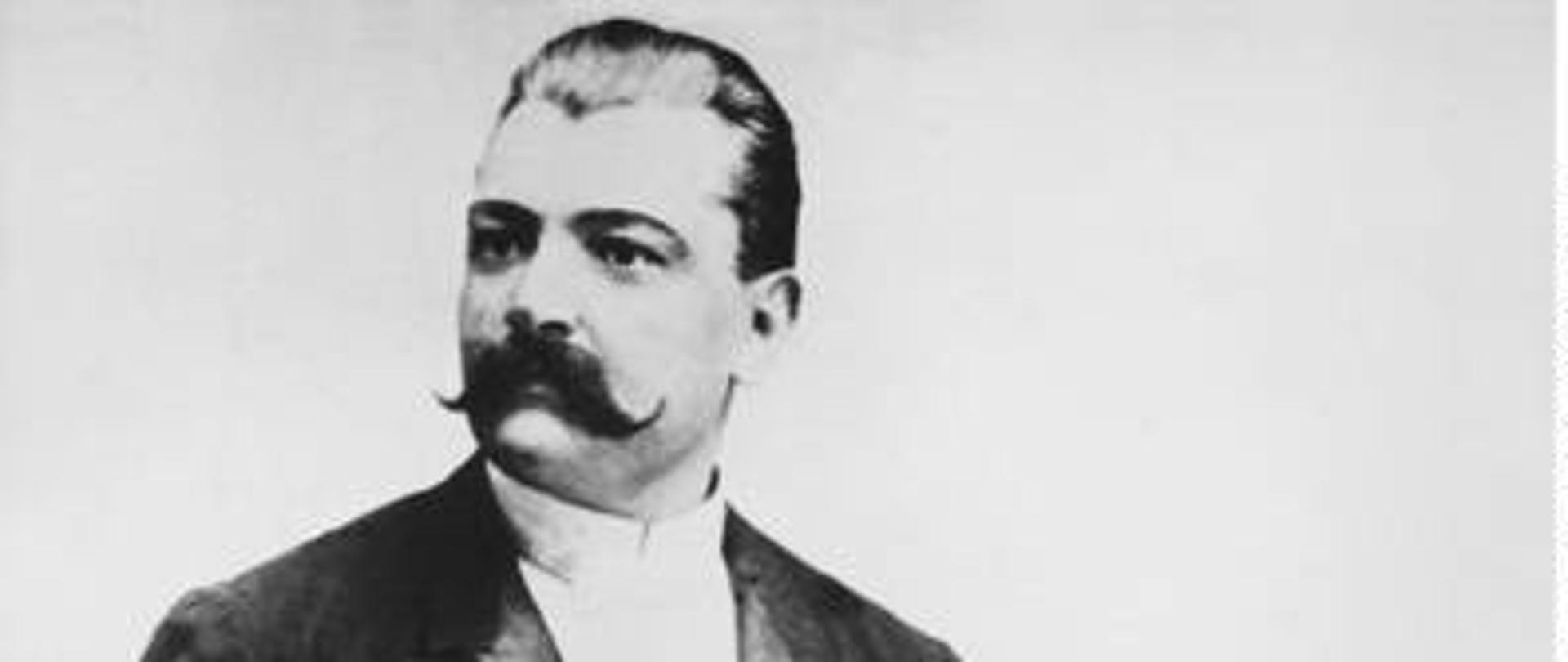 Karol Namysłowski stoi patrząc w prawą stronę, w lewej ręce trzyma skrzypce oparte o biodro a w prawej ręce trzyma smyczek