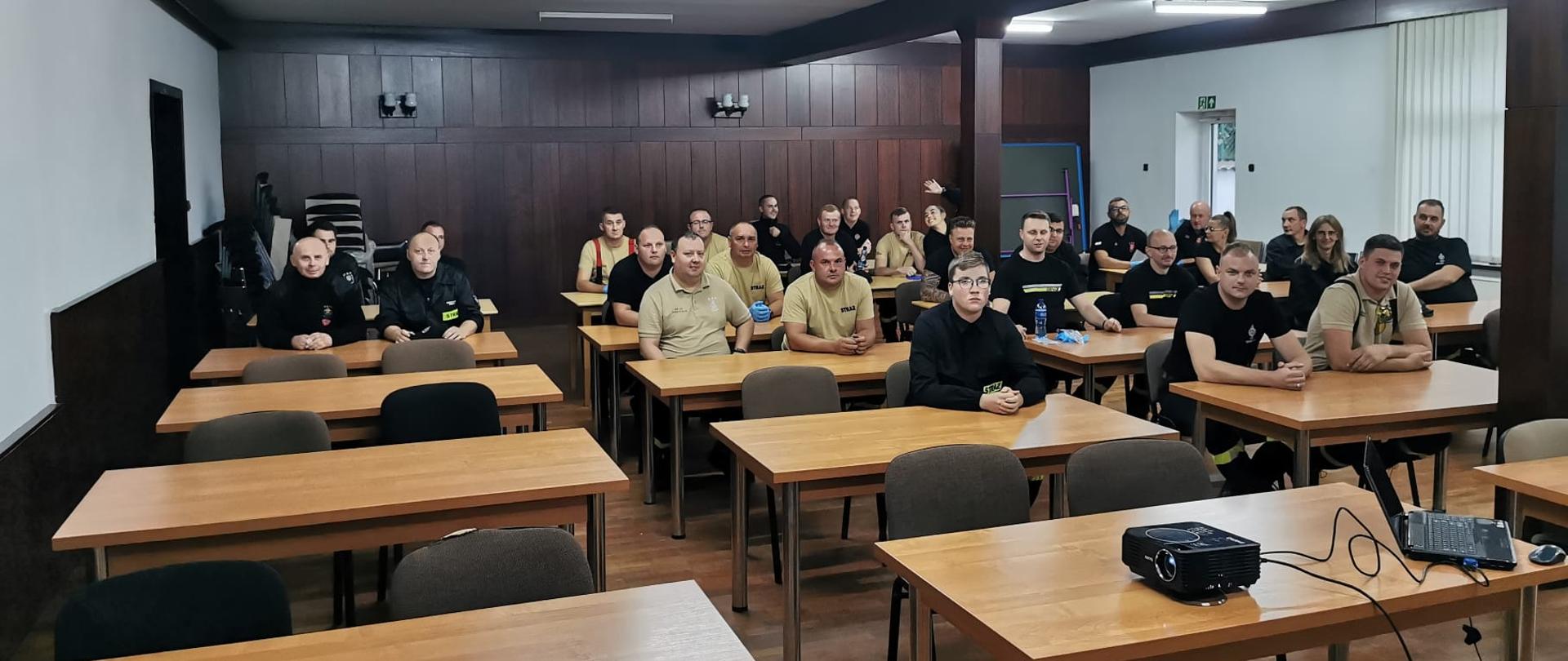 Druhowie siedzą w ławkach podczas egzaminu recertyfikacyjnego.