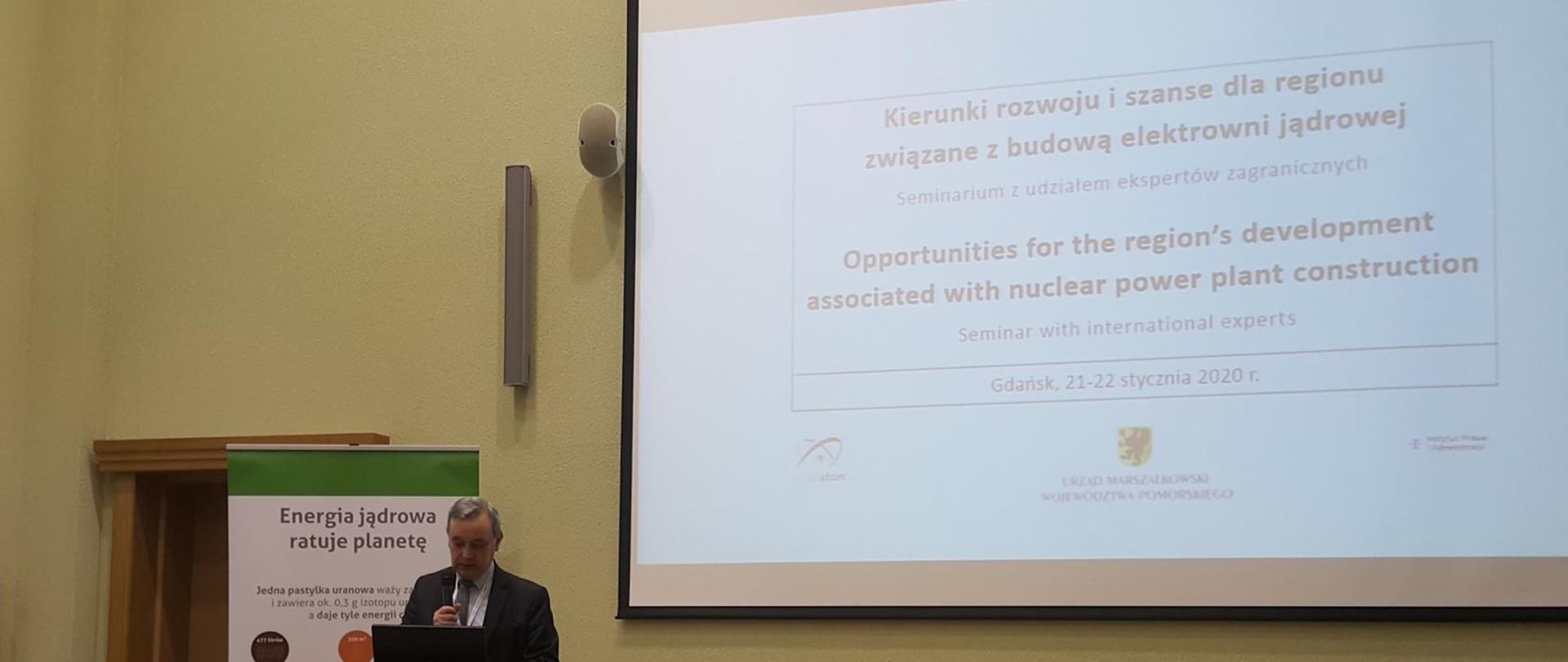 Zbigniew Kubacki - Zastępca Dyrektora Departamentu Energii Jądrowej w tle widoczna reklama stojąca z napisem Energia jądrowa ratuje planetę 