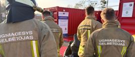 Szkolenia w ramach projektu LTPL00078 "Wzmocnienie współpracy litewskich i polskich służb ratowniczych w zakresie likwidacji awarii chemicznych i ekologicznych" - litewscy strażacy w trakcie szkolenia, ubrani w umundurowanie specjalne, w tle plakaty i banery dot. współpracy 