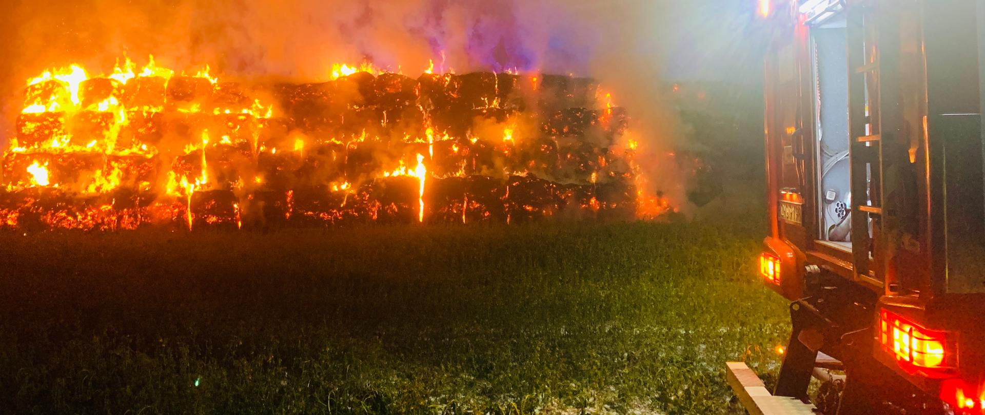 Stóg w całości objęty ogniem. Po prawej stronie tył samochodu strażackiego