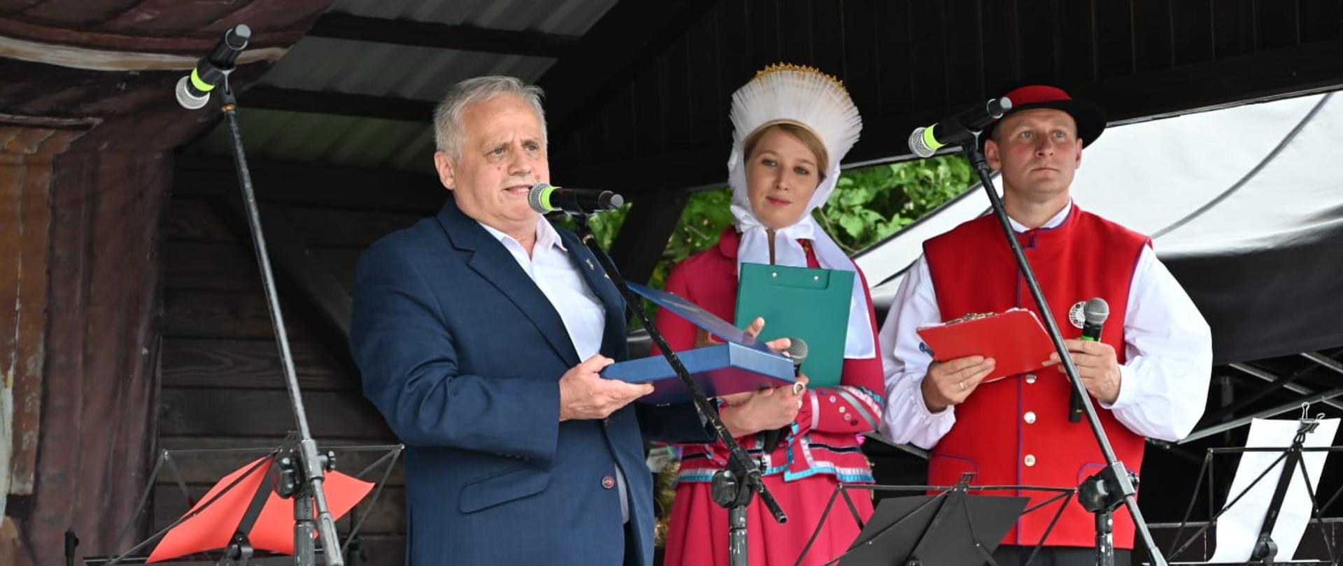 Trzy osoby stoją na scenie 