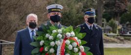Żołnierz Marynarki Wojennej składa wieniec w asyście wojewody pomorskiego oraz zastępcy pomorskiego komendanta wojewódzkiego PSP. 