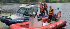 Dwie łodzie na rzece Wiśle - jedna policyjna, druga strażacka, na łodziach łącznie 4 osoby w kamizelkach. Pogodny dzień.