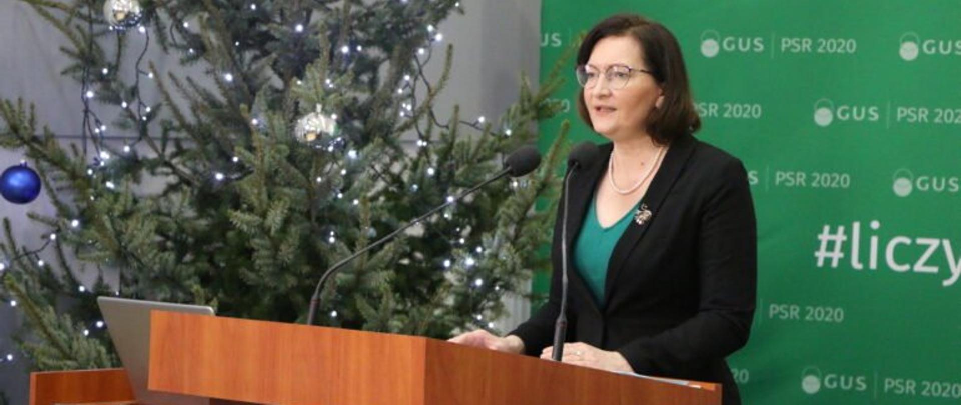Wojewoda podkarpacki Ewa Leniart przemawia podczas konferencji na temat wyzwań dla rolnictwa i obszarów wiejskich w świetle wyników Powszechnego Spisu Rolnego 2020, która odbyła się w Podkarpackim Ośrodku Doradztwa Rolniczego w Boguchwale. W tle zielona ścianka z napisani PSP 2020 i GUS. Obok choinka ubrana w srebrne i niebieskie ozdoby.
