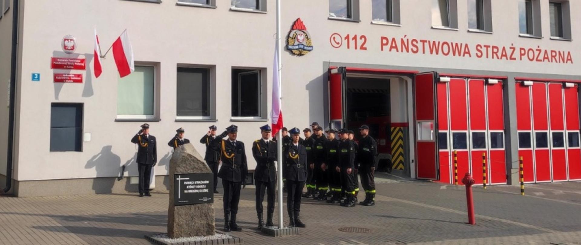Na zdjęciu widać strażaków Komendy Powiatowej PSP w Kolnie w momencie podnoszenia flagi państwowej.