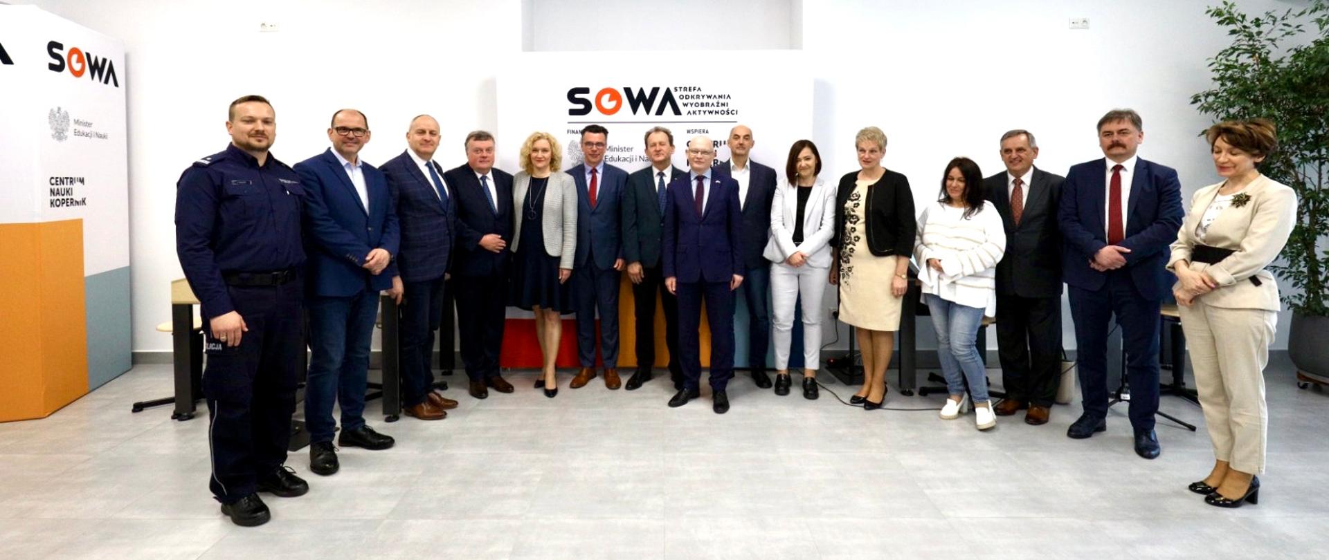 Zdjęcie zbiorowe uczestników uroczystości, stoją na tle ściany z napisem SOWA.