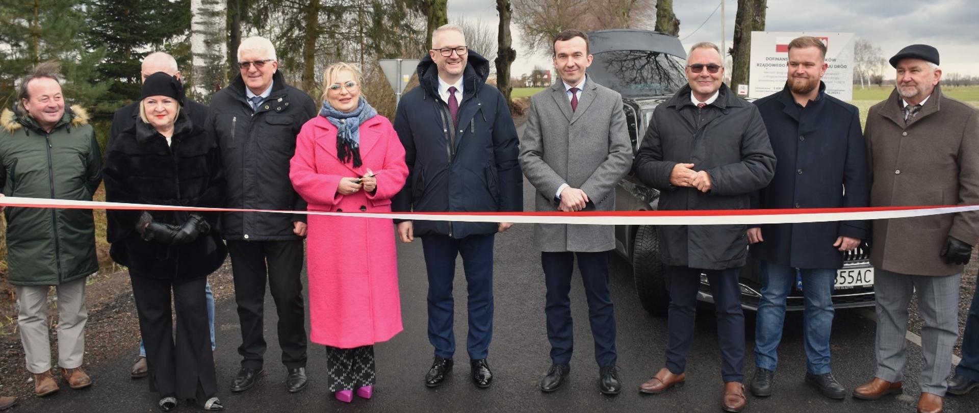 Grupa ludzi stoi na drodze i chce przeciąć wstęgę 