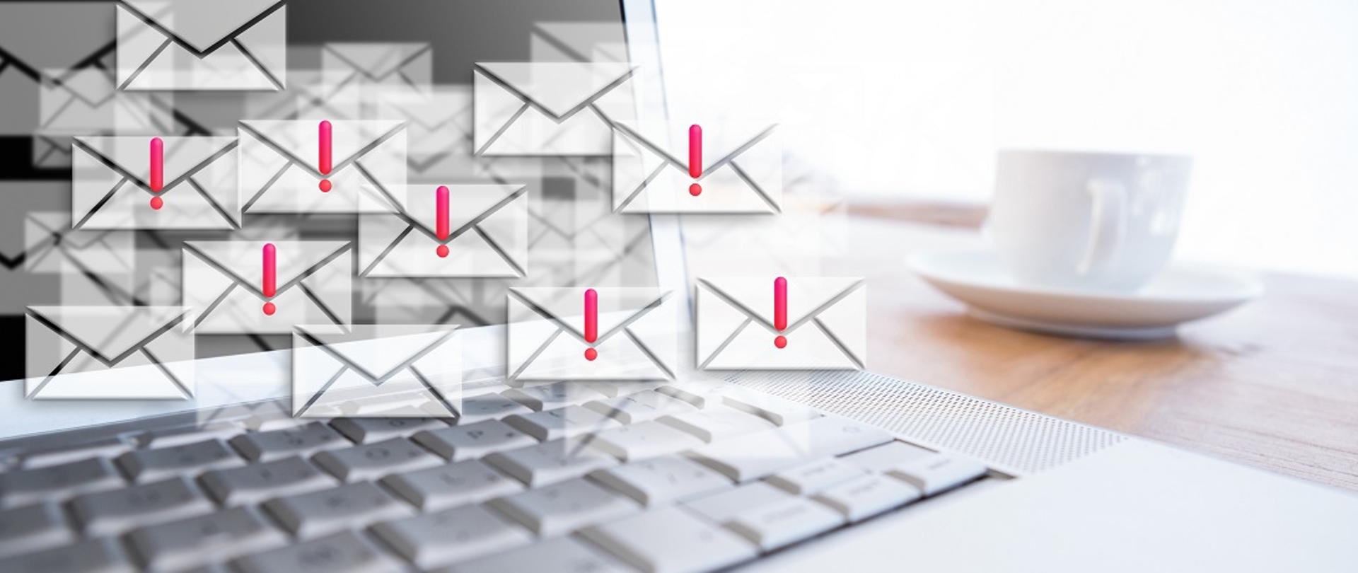 emaile w formie białych kopert z czerwonymi wykrzyknikami na tle laptopa