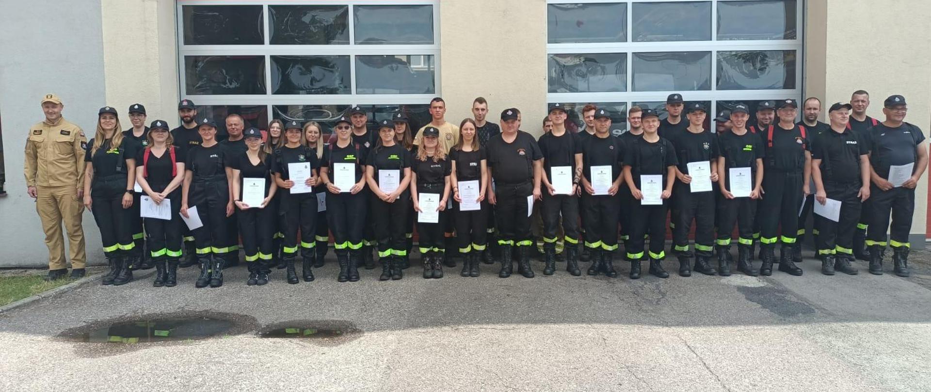 uczestnicy szkolenia podstawowego strażaków ratowników OSP na tle bram wjazdowych komendy