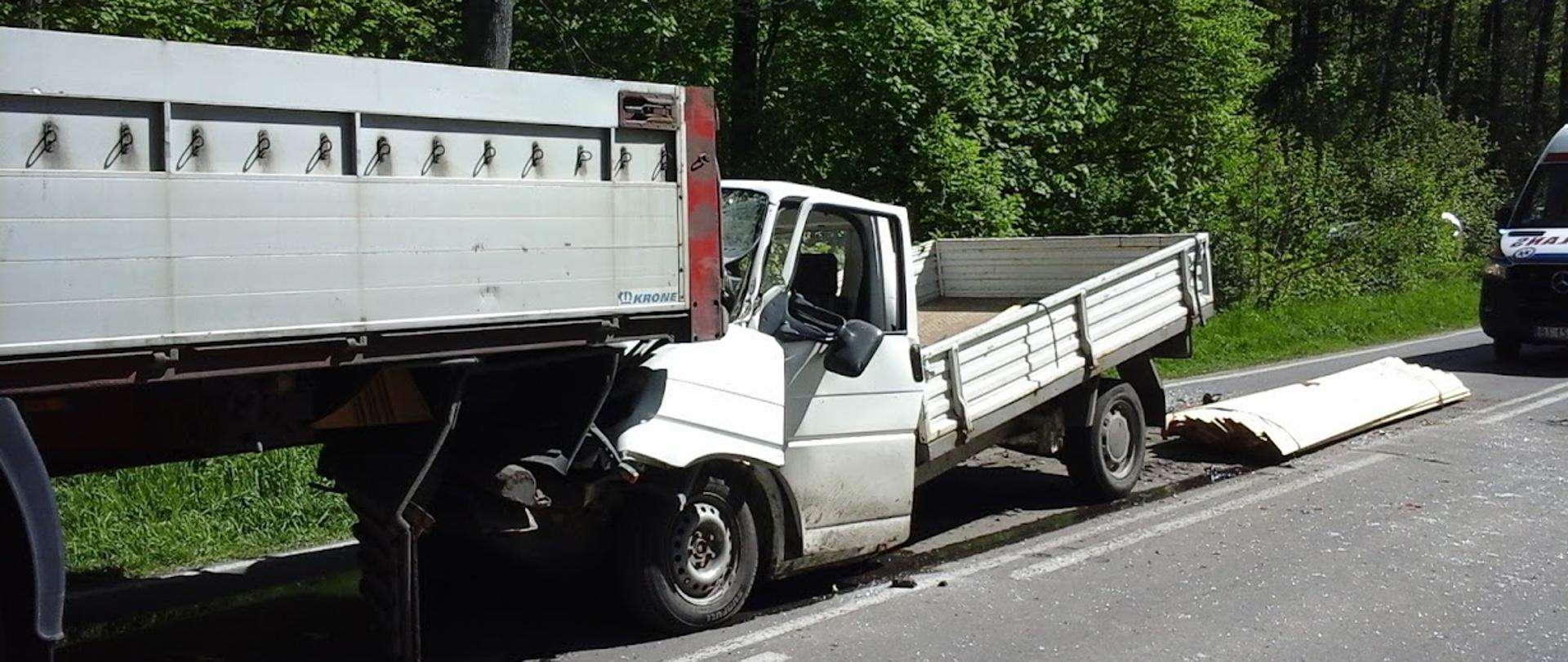 Uszkodzony samochód dostawczy, który wjechał w tył samochodu ciężarowego. Komora silnikowa samochodu dostawczego wbiła się pod tył samochodu ciężarowego.