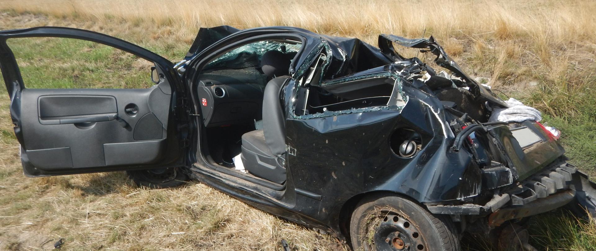 Zdjęcie przedstawia czarny samochód osobowy, który brał udział w zdarzeniu. Samochód znajduje się na poboczu autostrady.