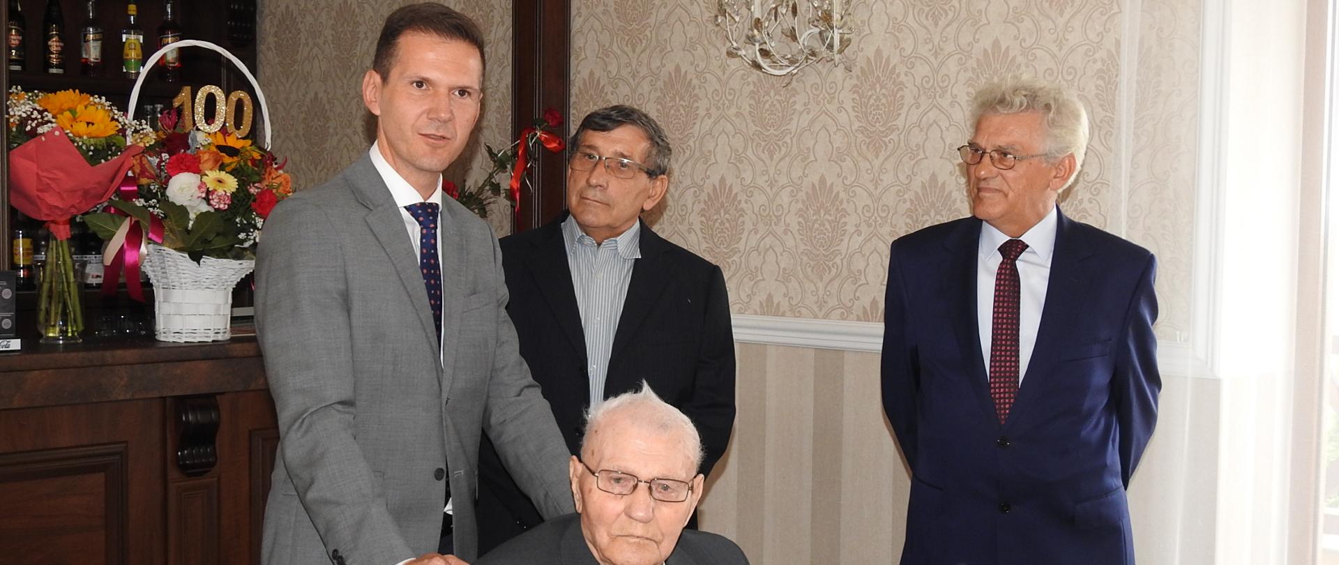 Jeden mężczyzna siedzi, trzech stoi