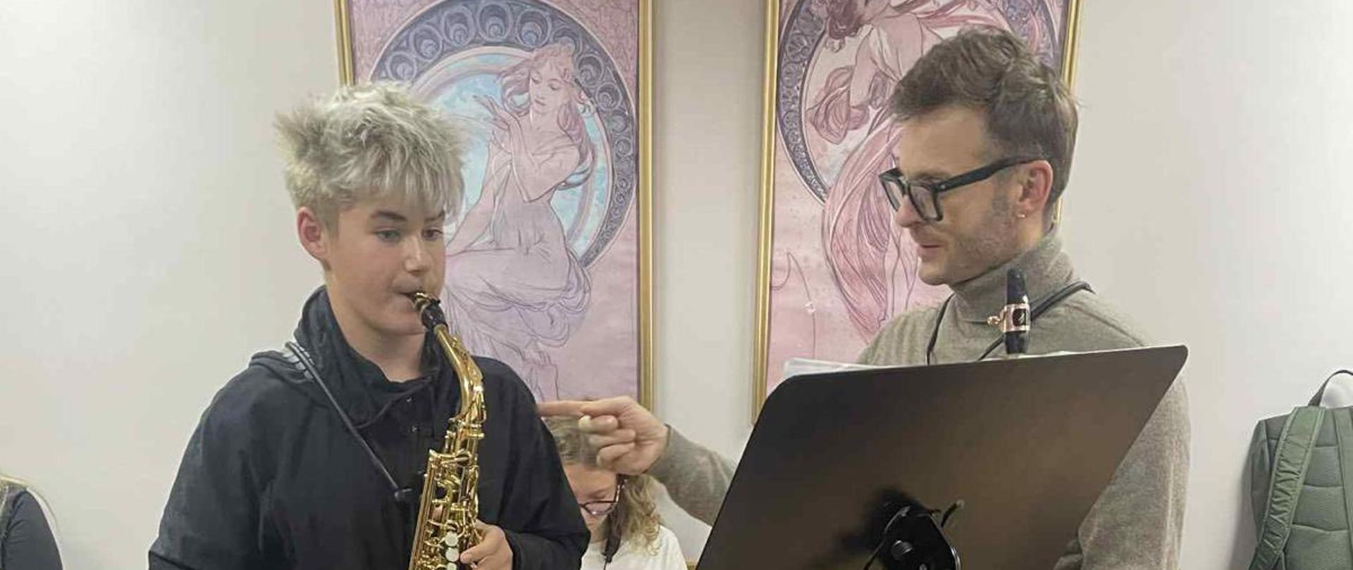 Uczeń podczas lekcji saksofonu, z prawej strony nauczyciel.