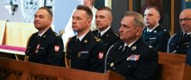 Zdjęcie przedstawia strażaków siedzących w ławkach podczas mszy świętej