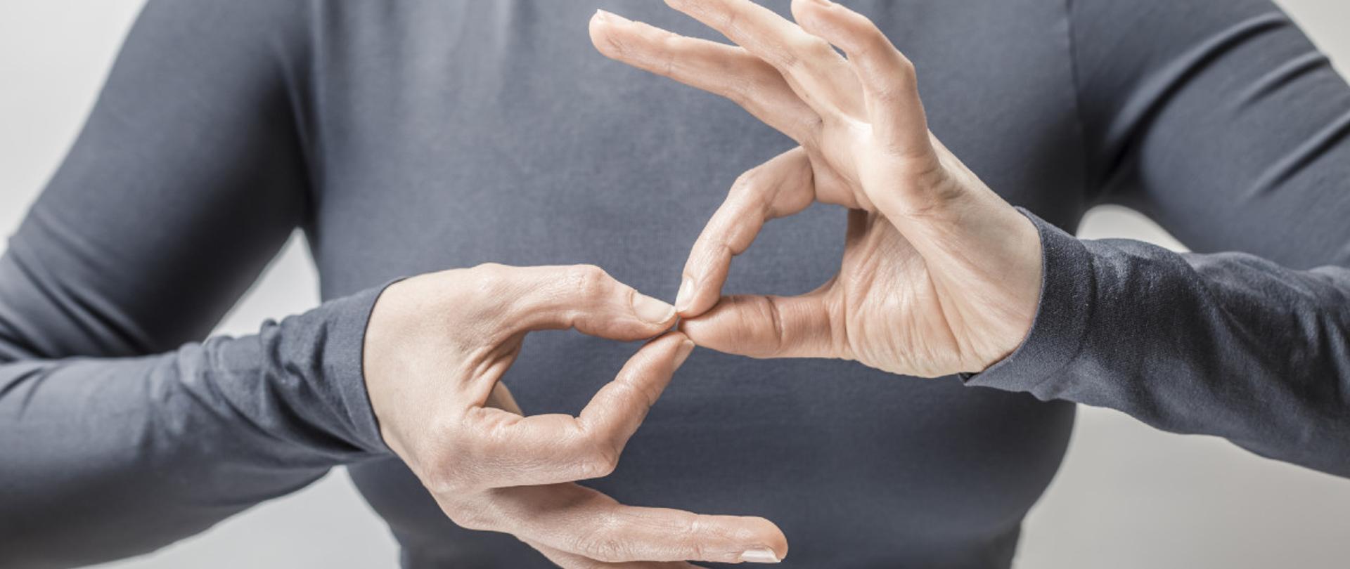 Kobieta, która mówi coś w języku migowym. Na pierwszym planie dłonie. 