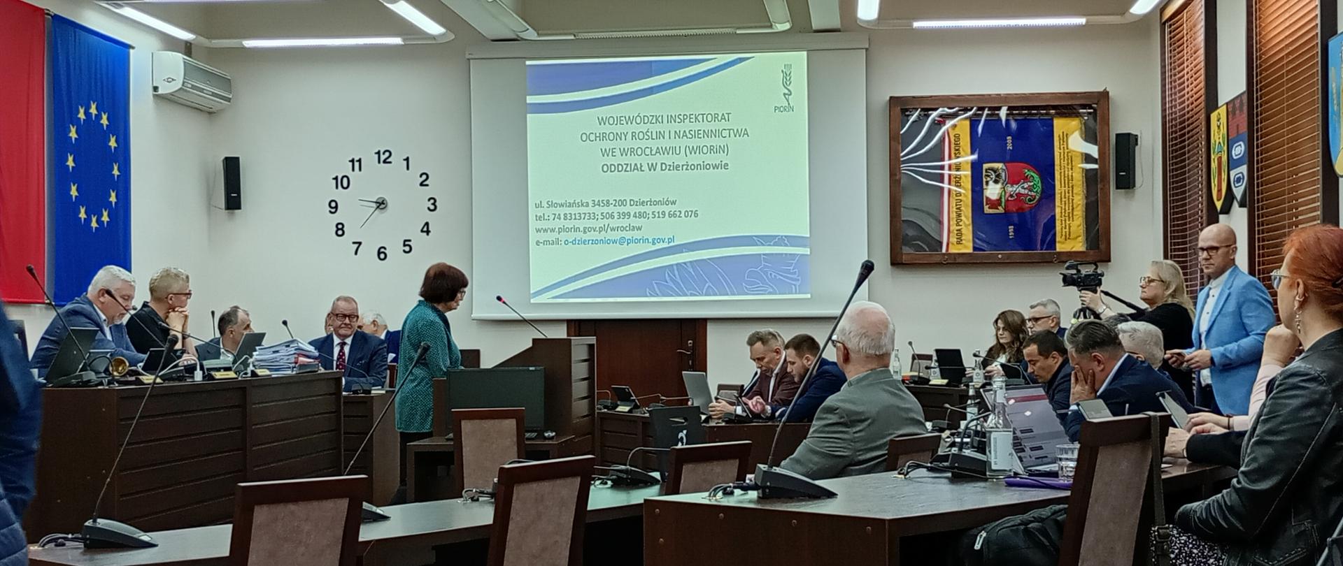 Sala konferencyjna z uczestnikami sesji, na środku widoczna prelegentka w trakcie wykładu