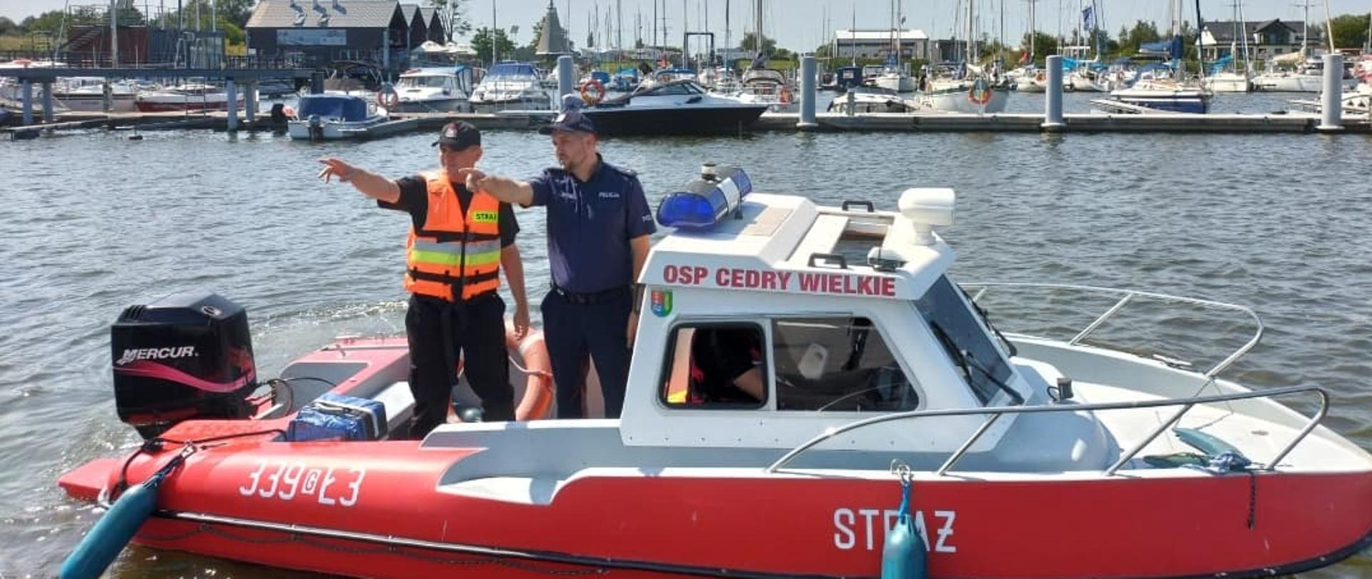 Zdjęcie przedstawia strażaka i policjanta, na strażackiej łódce podczas patrolowani kąpieliska 