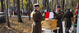 Żołnierze składają flagi Polski stoją przy każdej trumnie.