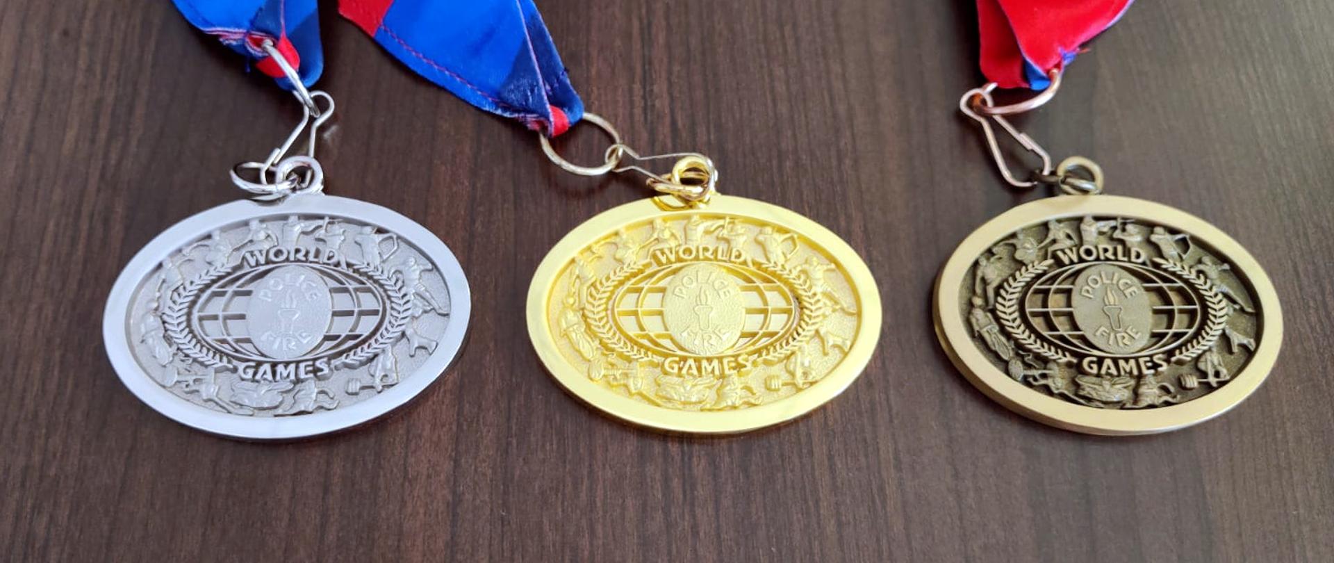 Zdjęcie przedstawia srebrny, zloty i brązowy medal Światowych Igrzysk Policjantów i Strażaków w Hadze