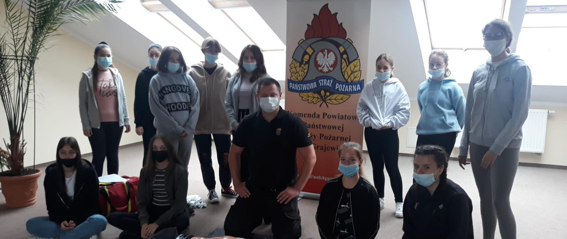 Zdjęcie grupowe. Uczestniczki warsztatów i prowadzący. Przed nimi leży fantom. W tle baner PSP.