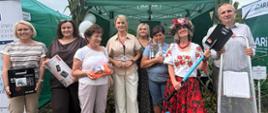 Przed stoiskiem prewencyjnym Kasy stoi grupa ludzi (siedem kobiet i mężczyzna) – laureatów Konkursu trzymających w rękach wygrane nagrody. Pośrodku stoi Kierownik PT KRUS w Krośnie.