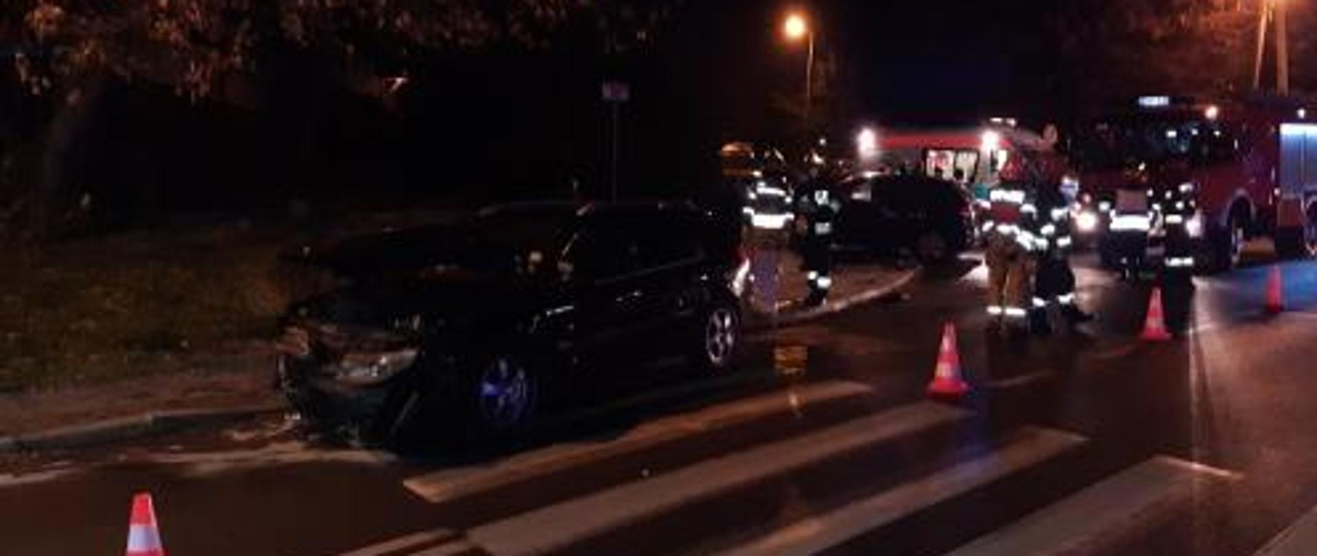 na zdjęciu na drodze samochód osobowy po wypadku drogowym. W pobliżu strażacy. W tle samochód ratowniczo - gaśniczy oraz karetka pogotowia.