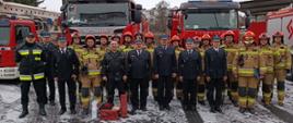 Zdjęcie grupowe strażaków na tle samochodów bojowych
