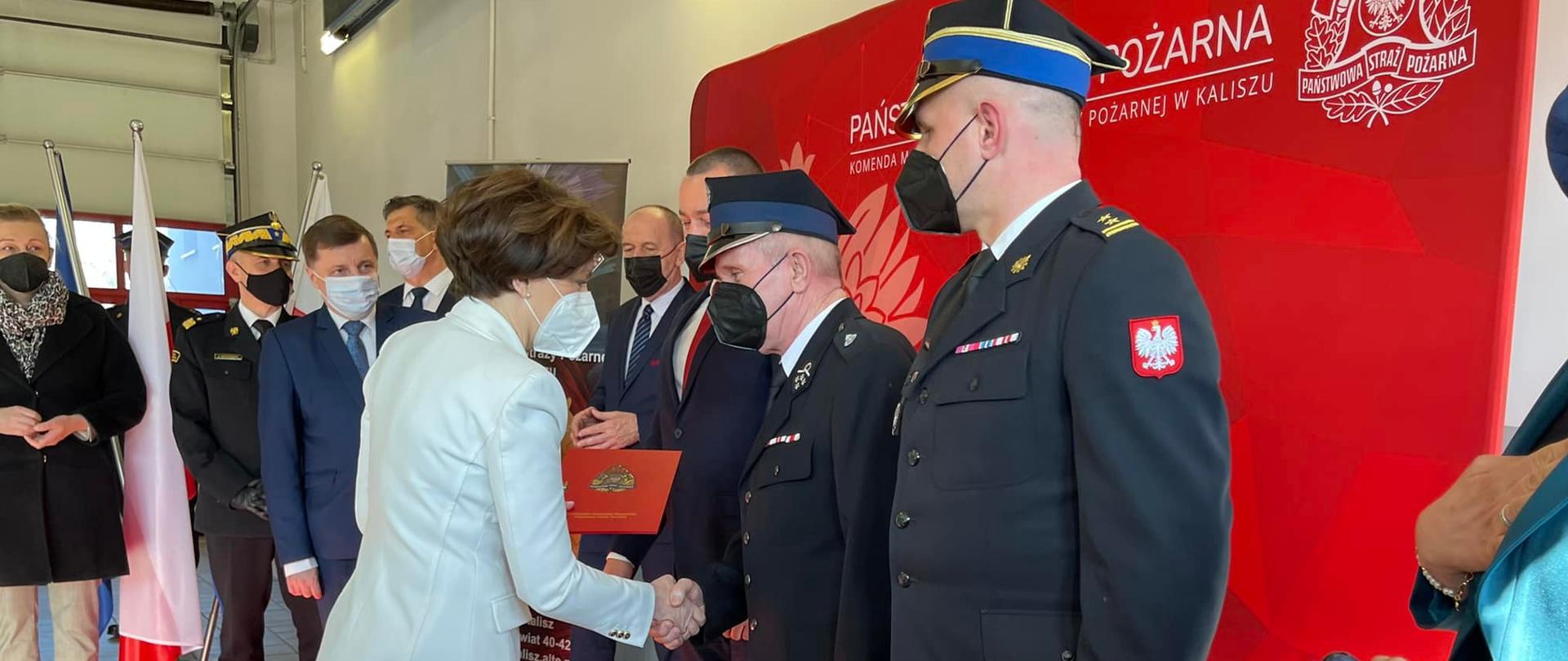 Zdjęcie przedstawia moment wręczenia promesy na zakup samochodu ratowniczo-gaśniczego. Promesy wręcza Pani Marlena Maląg prezesowi jednostki OSP Kuklinów. Prezesowi towarzyszy burmistrz Kobylina oraz komendant powiatowy PSP w Krotoszynie