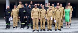 Pamiątkowe zdjęcie grupowe funkcjonariuszy PSP będących uczestnikami szkolenia dla kierowców pojazdów uprzywilejowanych (16 osób) w towarzystwie Zastępcy Komendanta Centralnej Szkoły PSP, kobiety oraz dwóch oficerów CS PSP