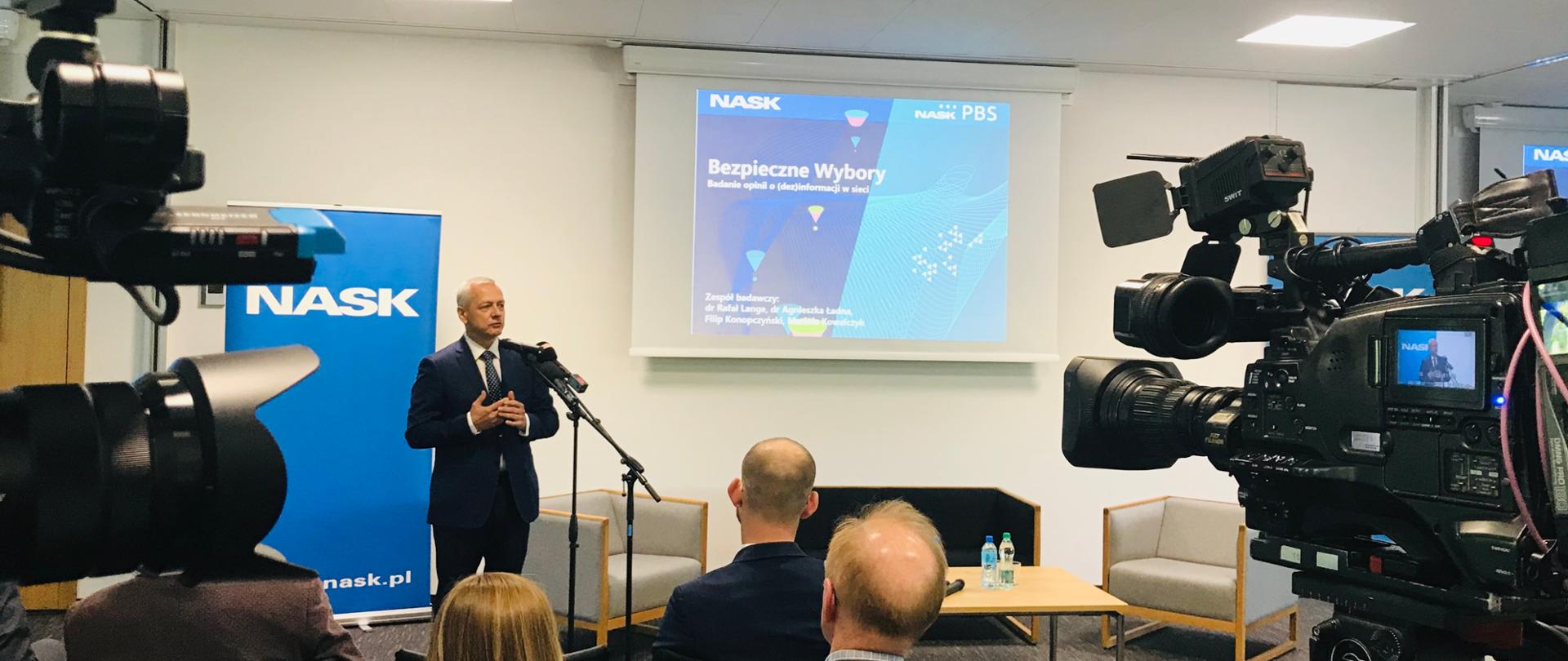 Minister Marek Zagórski, słuchacze i uczestnicy konferencji, kamery, banner NASK