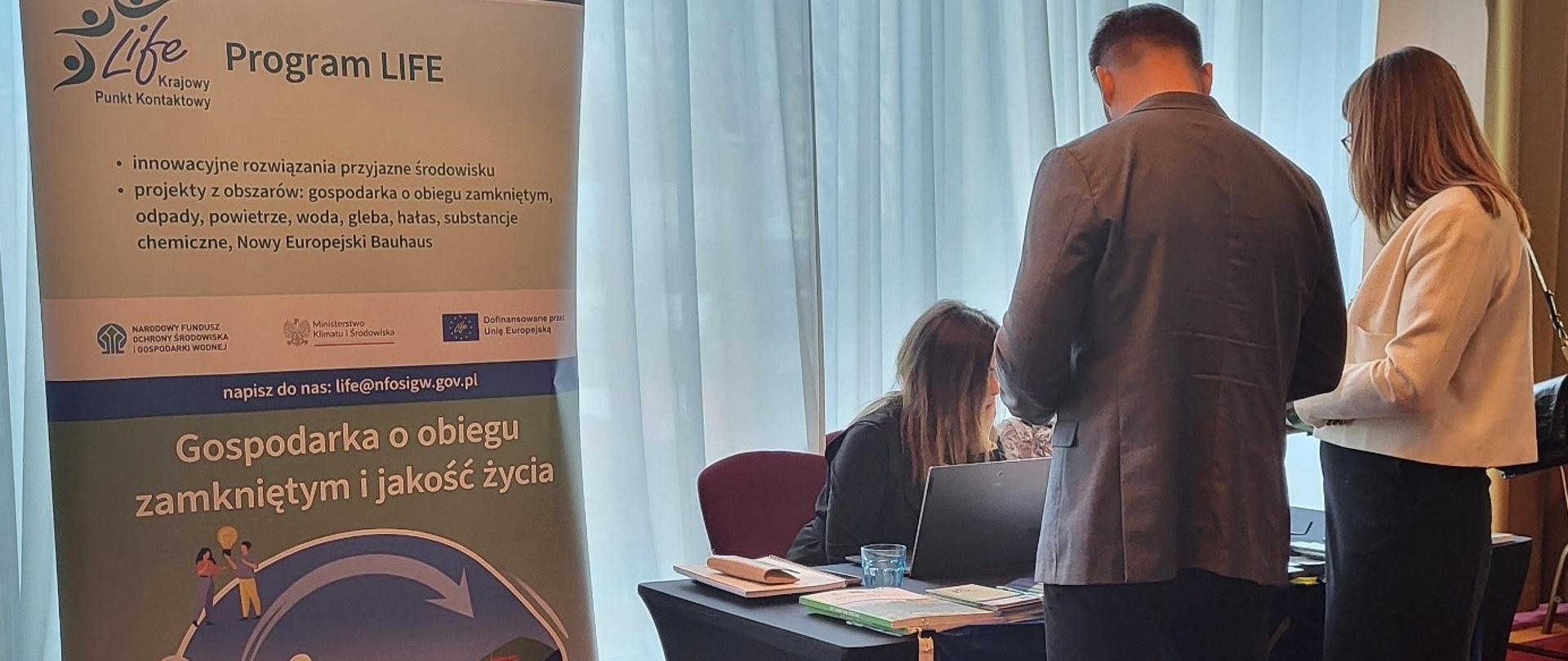 Obraz zawierający roll-up Programu LIFE, zespół KPK LIFE i uczestników Konferencji.