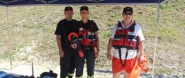 strażacy w kamizelkach ratunkowych na plaży zbiornika wodnego