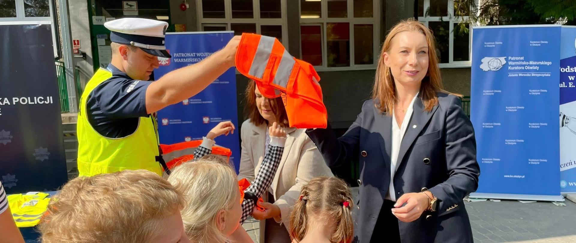 Dyrektor Generalny Monika Choroszewska-Plańkowska na rozpoczęciu Roku Szkolnego w Szkole Podstawowej nr 12 w Olsztynie rozdaje kamizelki odblaskowe 
