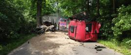 Zdjęcie przedstawia miejsce wypadku na drodze wojewódzkiej nr 297. Na zdjęciu widoczny jest samochód ciężarowy po wypadku - oderwana kabina pojazdu leży na drodze. W tle widocznych jest dwóch strażaków oraz samochód z Jednostki Ratowniczo-Gaśniczej z Lwówka Śląskiego. 