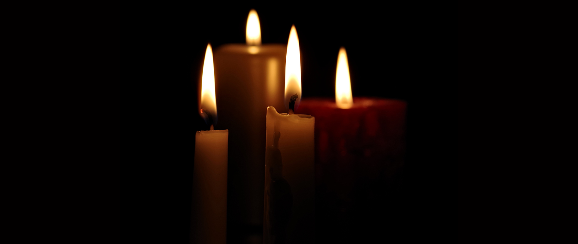 Zdjęcie zapalonych świec na czarnym tle.
