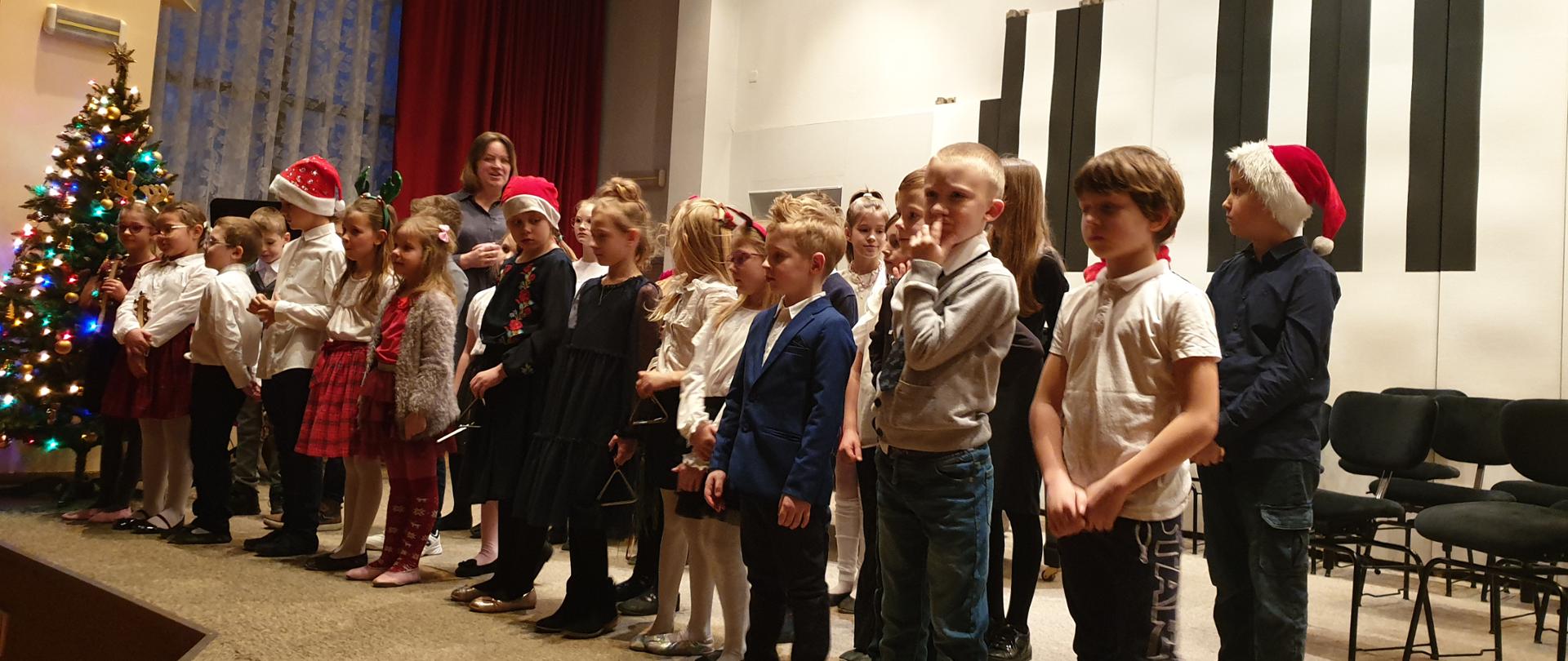 Dzieci z klas I i III c6z nauczycielem na scenie auli PSM