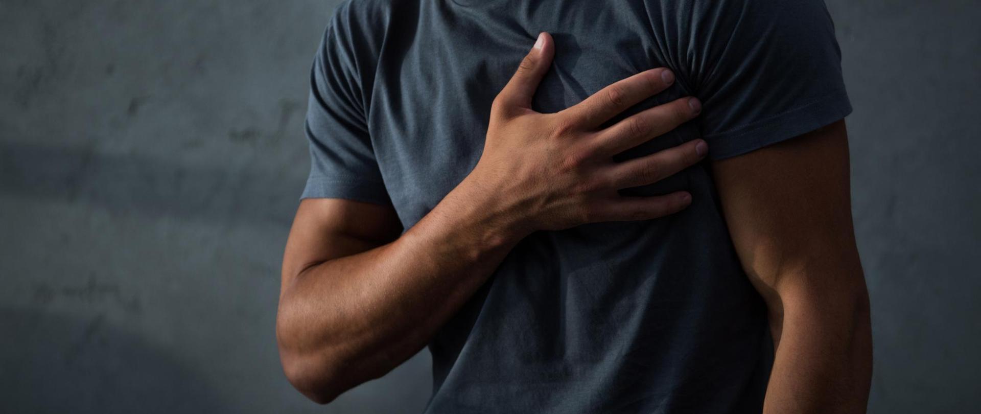 Na zdjęciu jest mężczyzna, który trzyma dłoń na klatce piersiowej, na wysokości serca.