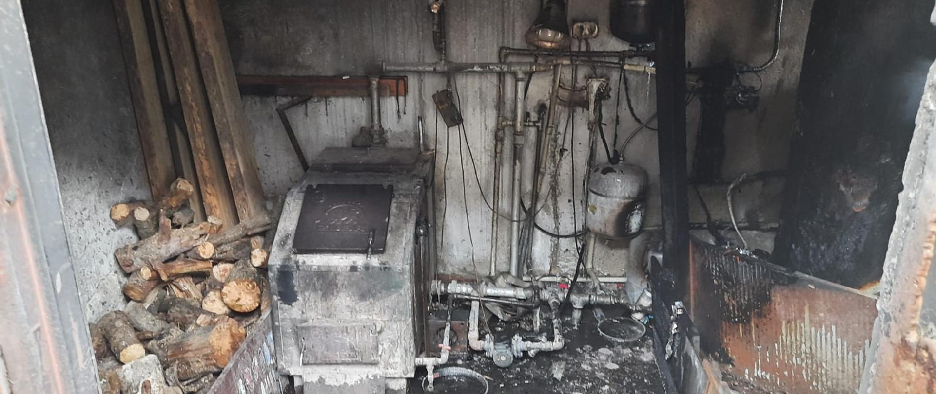Widać uszkodzone po pożarze pomieszczenie kotłowni oraz wyposażenie pieca