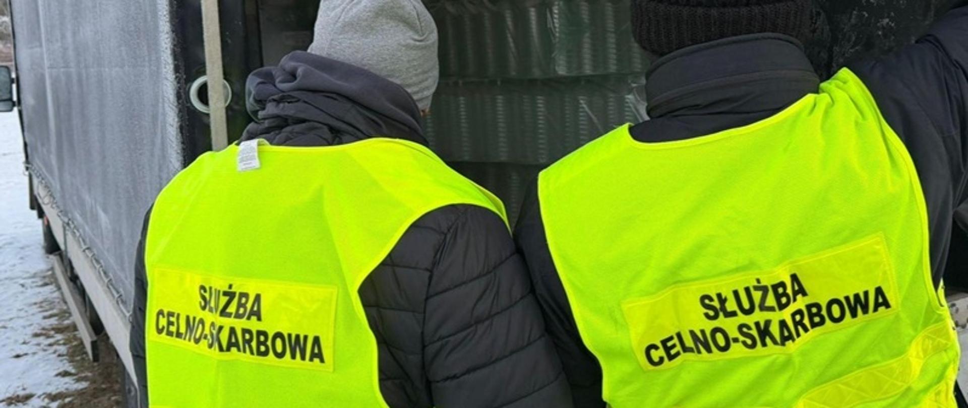 Funkcjonariusze oglądają towar zabezpieczony w nielegalnej rozlewni alkoholu.