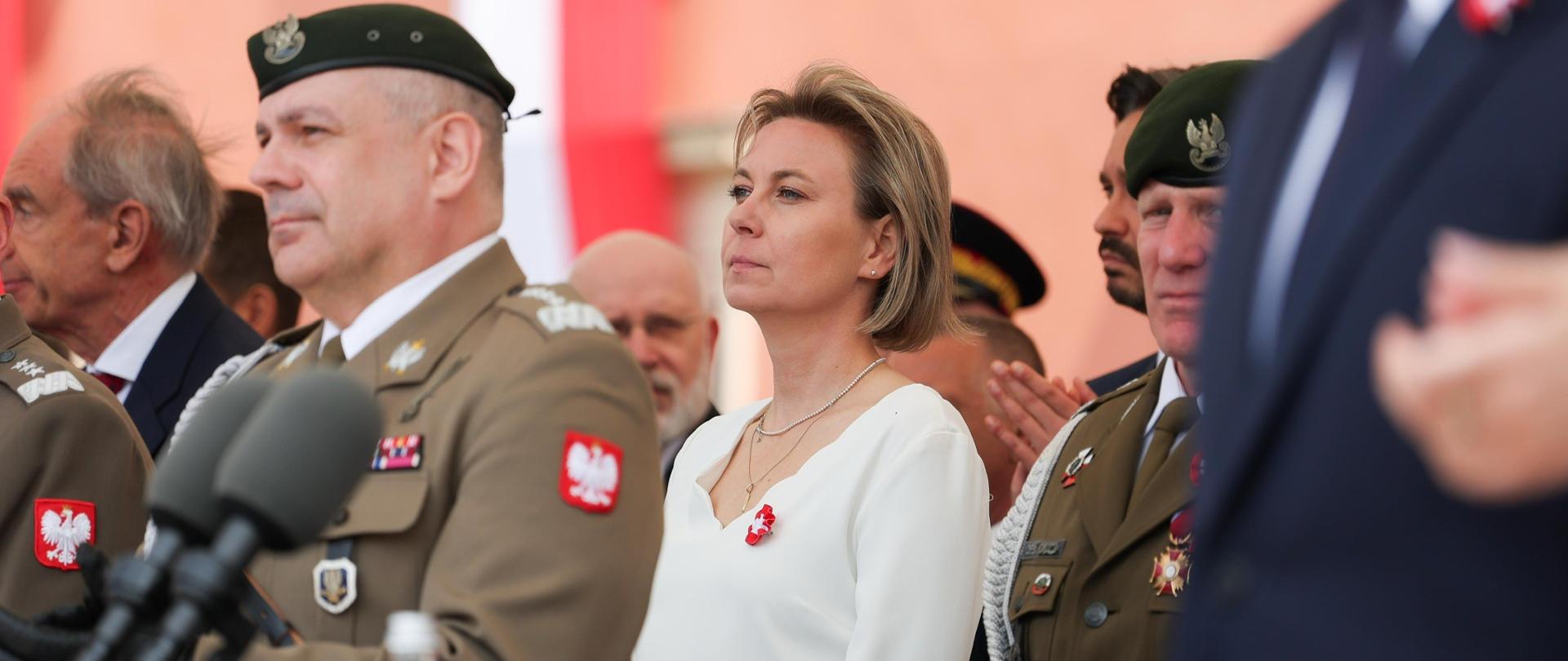 Fotografia przedstawia Ministrę Adrianę Porowską oraz innych uczestników centralnych obchodów Święta Narodowego Trzeciego Maja na placu Zamkowym w Warszawie. 