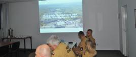 Widok wyświetlanej prezentacji i części strażaków biorących udział w spotkaniu