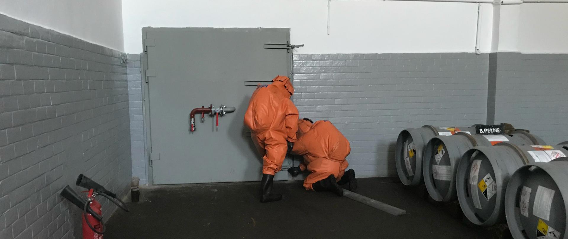ćwiczenia chemiczne w Stacji Uzdatniania Wody Zawada w Zielonej Górze - strażacy w specjalistycznym ubraniu zamykają śluzę