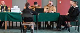 Eliminacje ogólnopolskiego turnieju wiedzy pożarniczej. Dziecko siedzi na etapie ustnym i odpowiada na pytania komisji. 