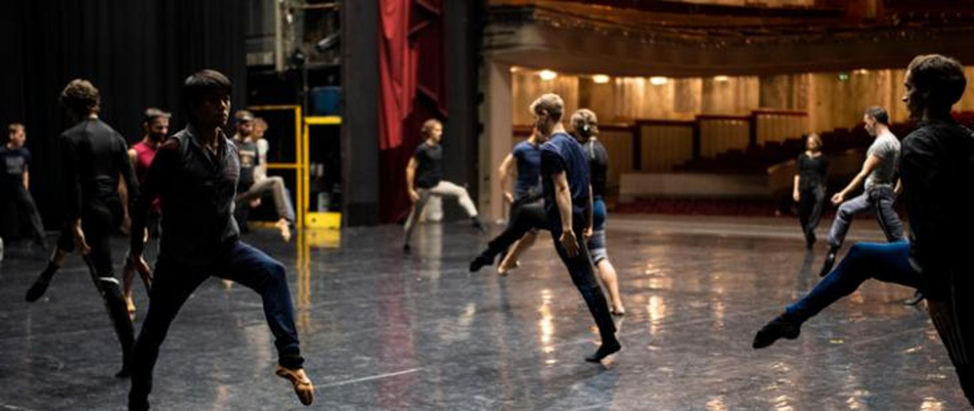 Aktorzy, tancerze na scenie. Próba - grupa mężczyzn wykonuje ruchy określone sekwencje ruchowe